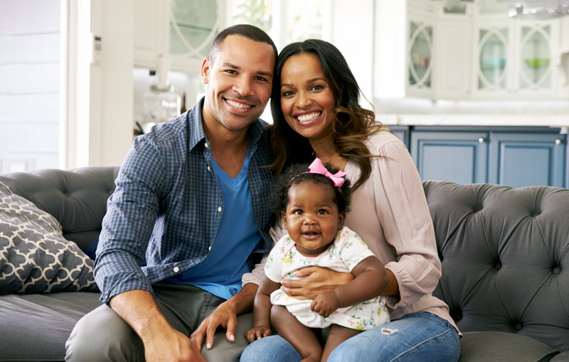 Happy parents with a baby girl sitting on her mother's lap